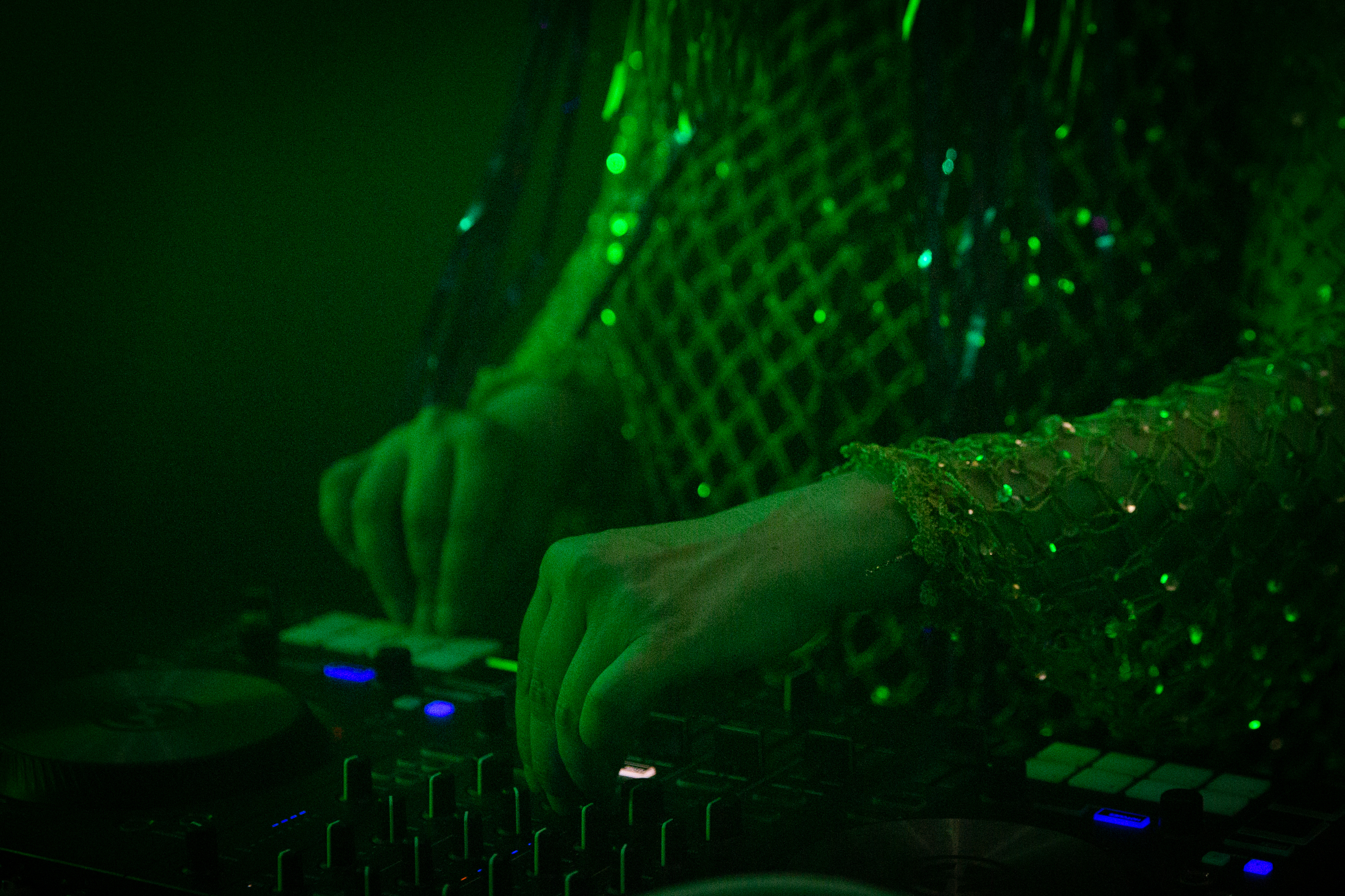 Deux mains au premier plan actionnent les touches d'une platine de DJ.