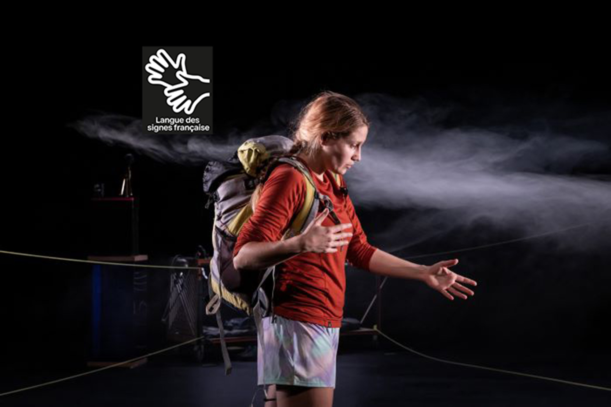 Comédienne de profil avec un sac à dos et de la brume qui passe autour d'elle.